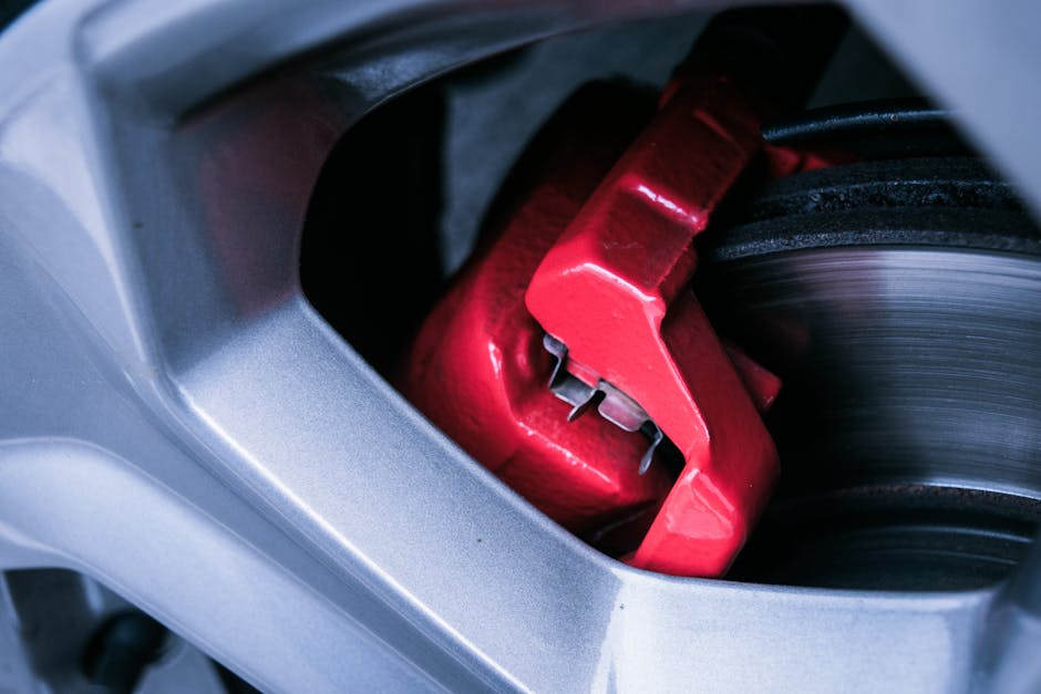Detailed photo of a red automotive brake caliper and disc brake in focus.