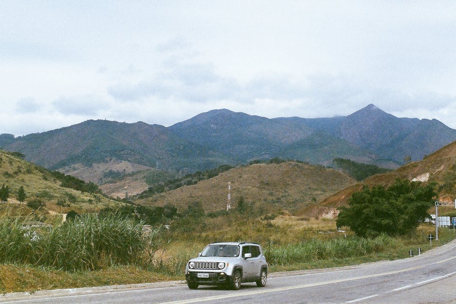 A car driving on a road with majestic mountains in the background, perfect for travel theme.
